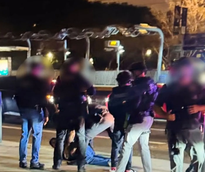 Law enforcement officers detain a person on the street at night related to Michelle Obama and fake syndrome claims. Law enforcement officers detain a person on the street at night related to Michelle Obama and fake syndrome claims.