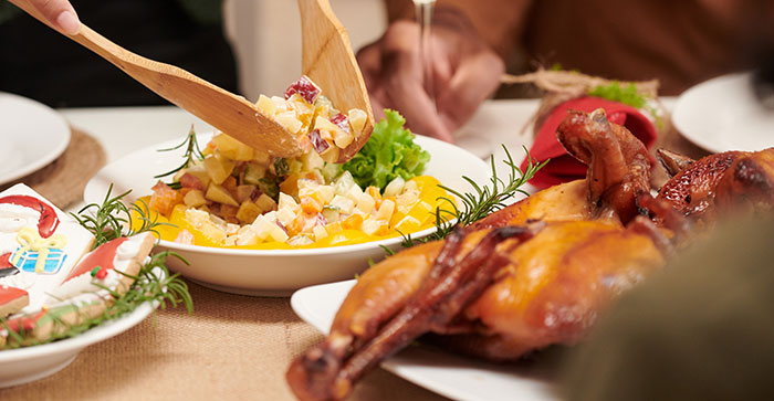 Hand serving traditional meat and potato salad on a holiday table with no vegan options Christmas Eve dinner. Hand serving traditional meat and potato salad on a holiday table with no vegan options Christmas Eve dinner.