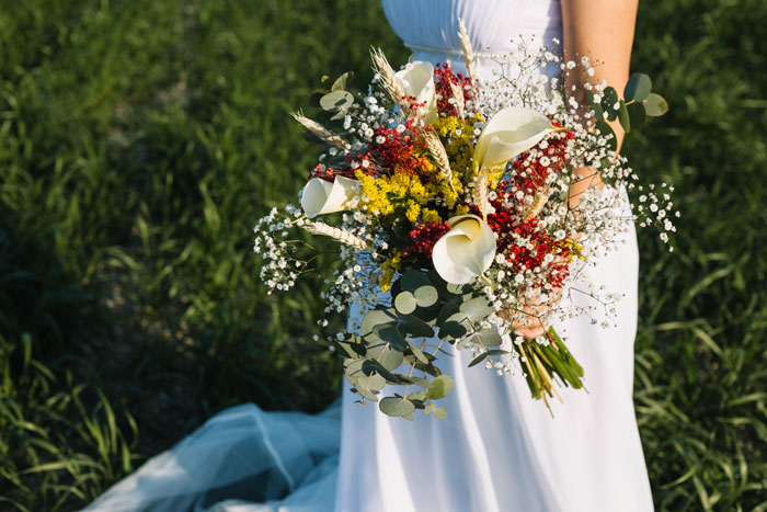 Bride holding a colorful wedding bouquet outdoors, capturing the moment with a focus on the bouquet and dress. Bride holding a colorful wedding bouquet outdoors, capturing the moment with a focus on the bouquet and dress.
