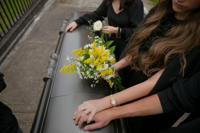 People in black holding flowers and hands on a coffin, reflecting on life facts that might make you do a double take.