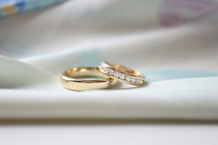 Two gold wedding rings on a soft fabric surface representing wedding cancellation concerns months before the big day.