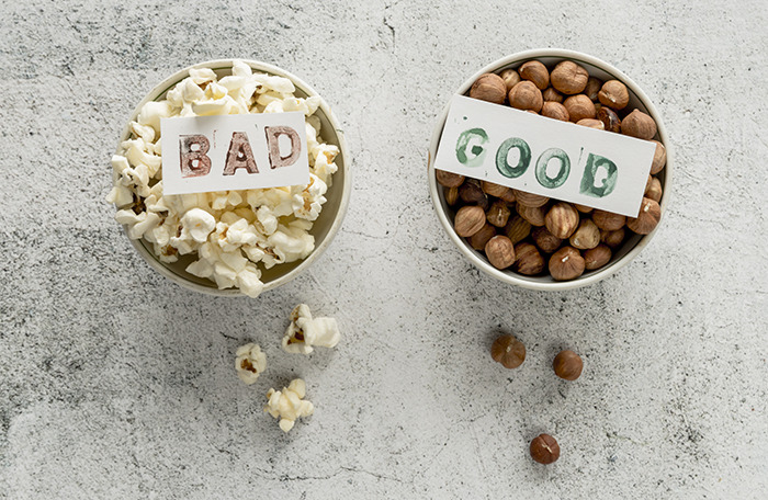 Two bowls on a gray surface, one with popcorn labeled bad and one with nuts labeled good, highlighting pseudoscience risks. Two bowls on a gray surface, one with popcorn labeled bad and one with nuts labeled good, highlighting pseudoscience risks.