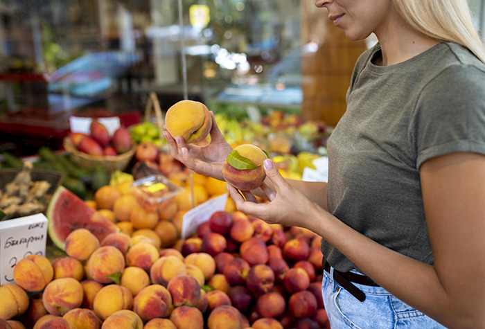 Woman in casual clothes selecting fresh peaches at a market, illustrating a story on pseudoscience and tragic consequences. Woman in casual clothes selecting fresh peaches at a market, illustrating a story on pseudoscience and tragic consequences.