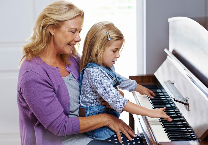 Woman teaching young girl to play inherited piano, symbolizing parents donating piano to church in an emotional moment.