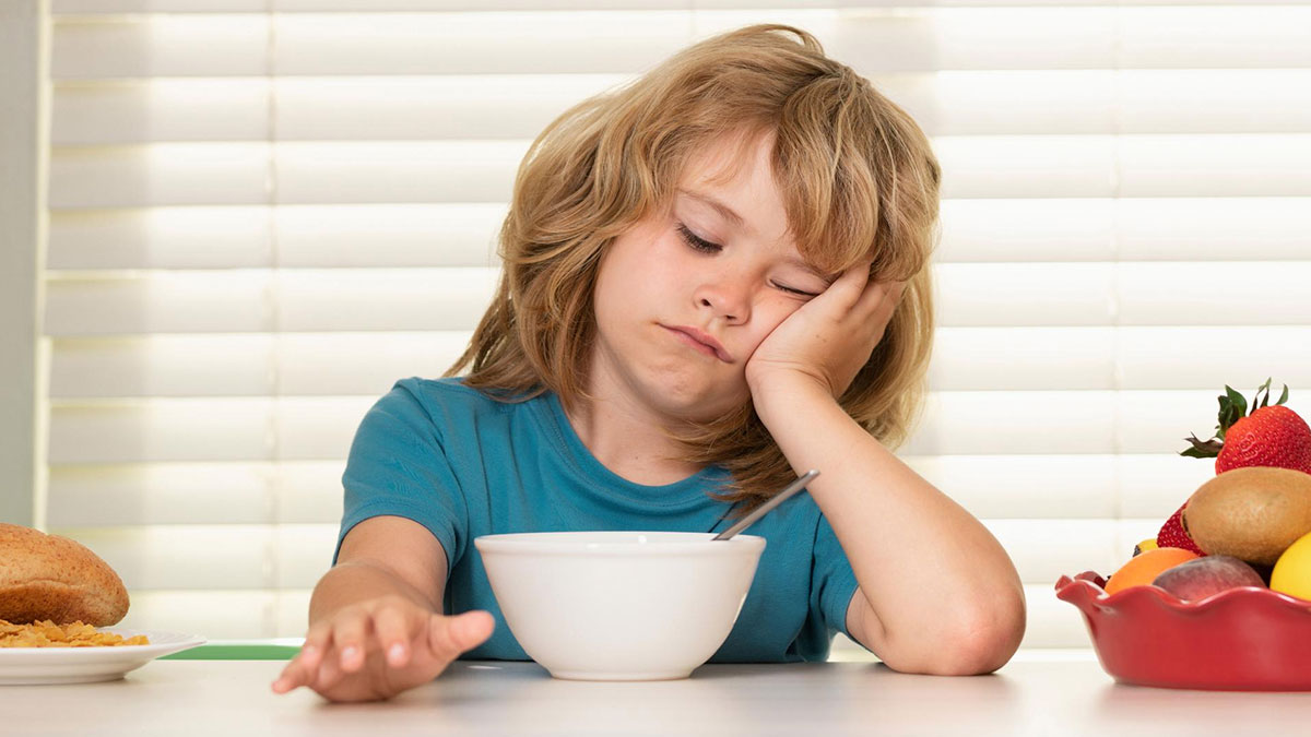 Young child looking reluctant to eat breakfast, illustrating common issues when parents lied about allergies.