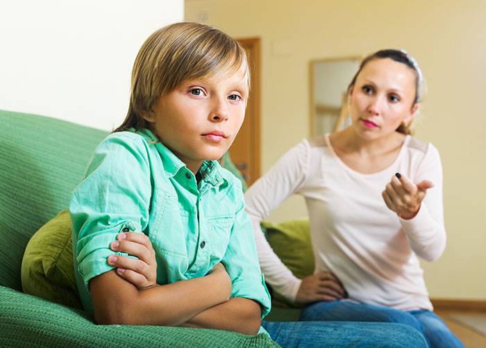 Mother confronting a selfish child with arms crossed, showing unloving behavior and tension in a home setting.