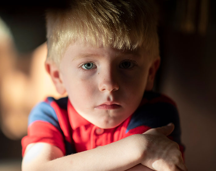 Sad young boy with a serious expression symbolizing vain and selfish unloving sociopath behavior in children.