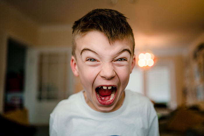 Young boy screaming angrily indoors, expressing emotions linked to selfish and unloving sociopath behavior.