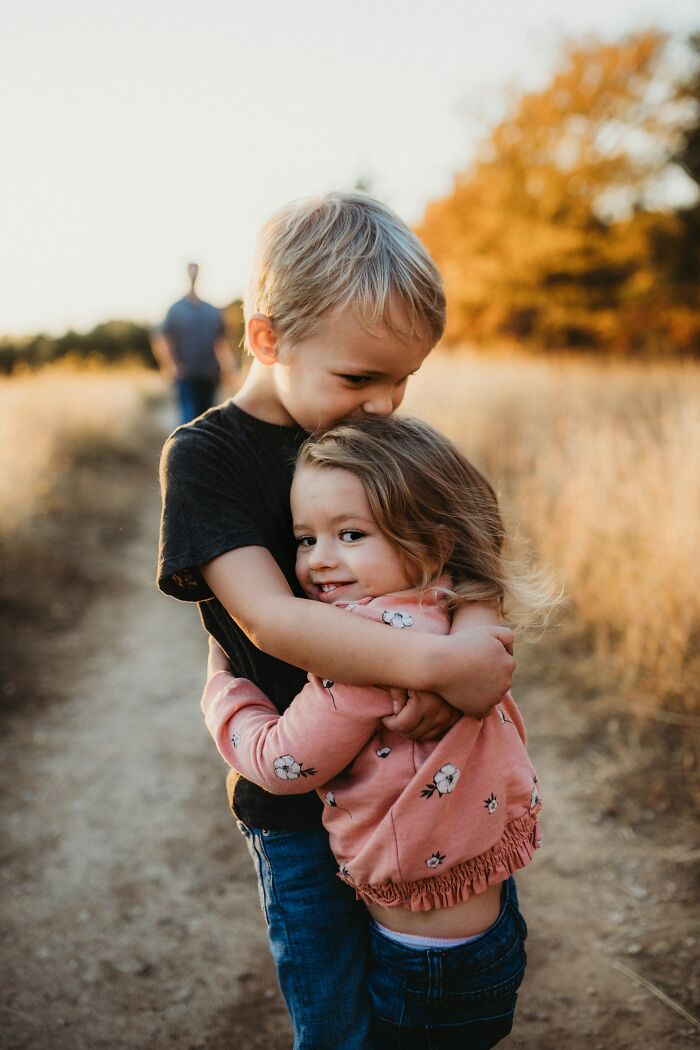 Two young children hugging outdoors on a path during golden hour, illustrating modern parenting trends in family bonding.