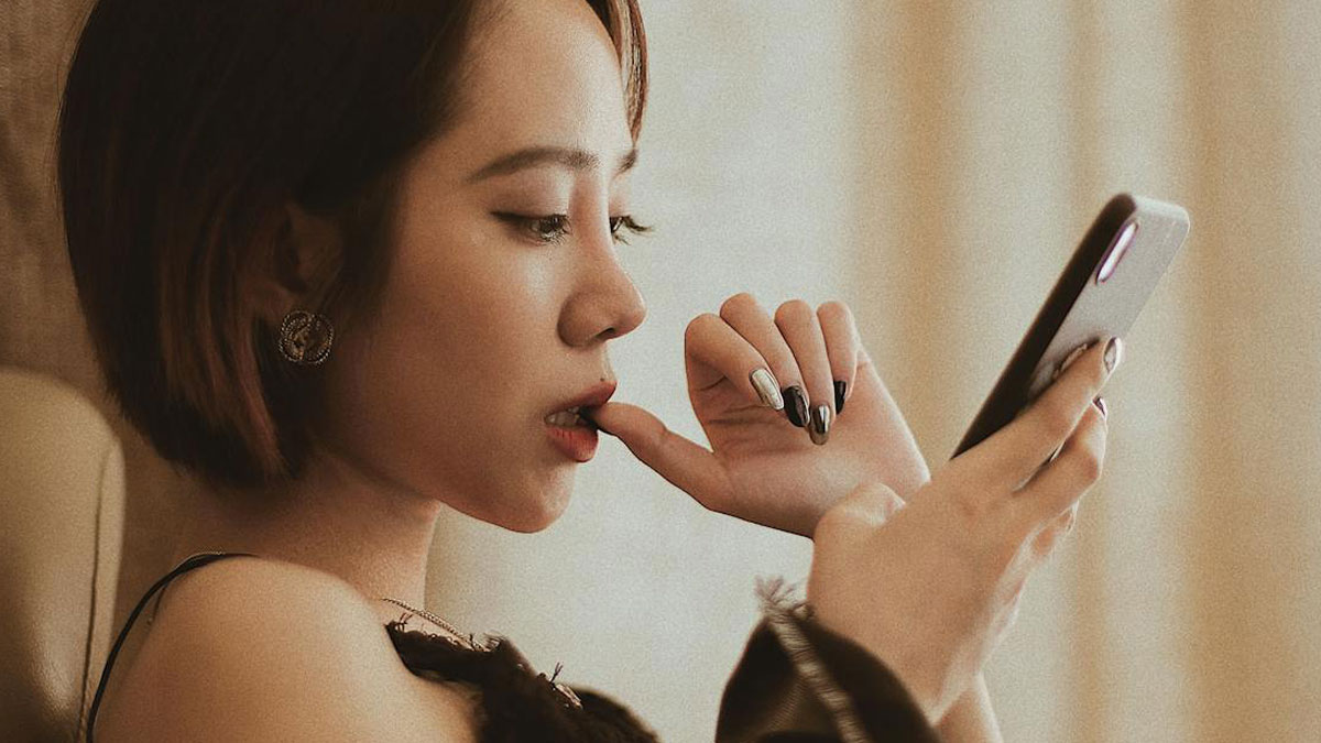 Young woman looking surprised and disturbed while reading disturbing facts on her smartphone.