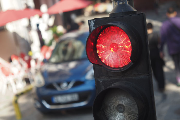 Red traffic light on a busy street with a car and pedestrians, capturing a moment linked to scariest moments trauma.