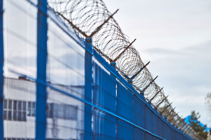 Blue security fence topped with barbed wire symbolizing scary moments that left people traumatized.