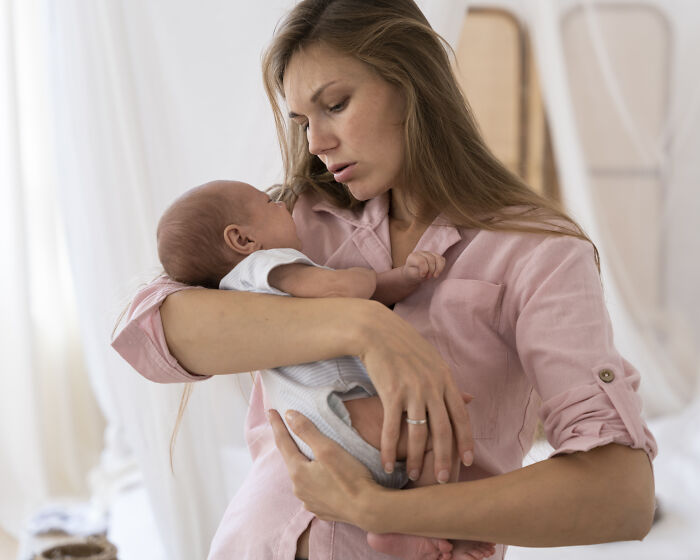 Woman holding newborn baby with worried expression, capturing a moment people saw something so scary and still talk about it.