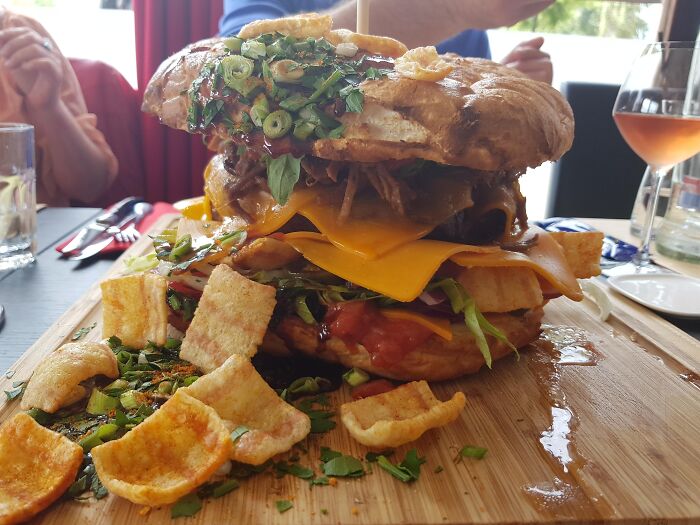 Close-up of a hearty sandwich with cheddar cheese, greens, and crispy chips, showcasing dishes that didn’t need a gourmet upgrade.