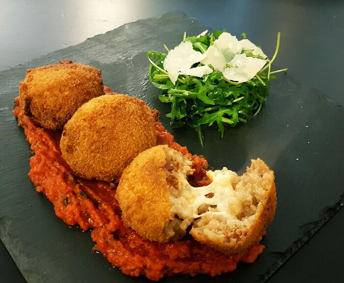 Crispy fried arancini with melted cheese, served with tomato sauce and fresh arugula salad with shaved parmesan.