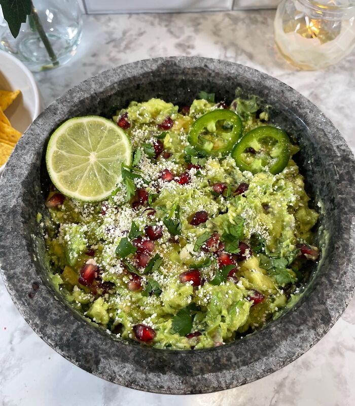 Guacamole with lime, jalapeño, pomegranate seeds, and cheese in a stone bowl, a dish foodies didn’t need gourmet upgrade.
