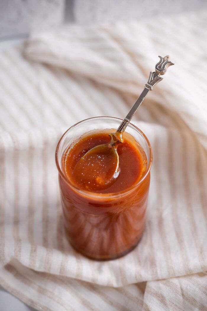Glass jar filled with caramel sauce and a decorative spoon, showcasing simple dishes foodies say didn’t need gourmet upgrades.