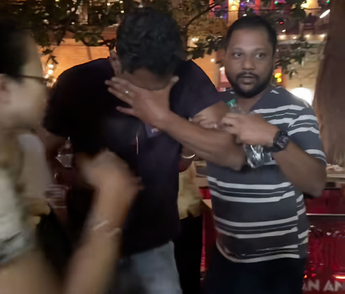 Man covering face being restrained by another man in striped shirt during chaotic moment involving pepper-spraying tourists on boat