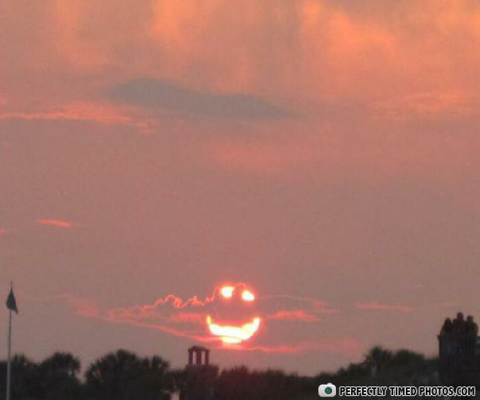 Sunset with clouds forming a perfectly timed smiley face over the horizon, showcasing an impressive natural photo moment.