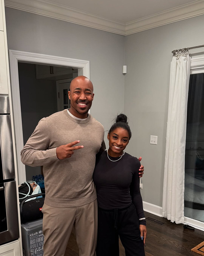 Simone Biles smiling indoors with a man, posing casually amid a home setting, related to painful dog ears controversy. Simone Biles smiling indoors with a man, posing casually amid a home setting, related to painful dog ears controversy.