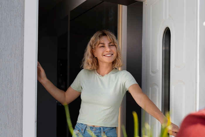 Young woman smiling at the doorway with sunlight, representing a friendly Karen Petty fence revenge moment outdoors. Young woman smiling at the doorway with sunlight, representing a friendly Karen Petty fence revenge moment outdoors.