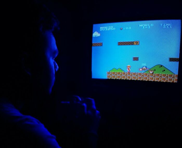 Person playing a retro video game late at night, illustrating true stories that sound made up but actually happened.