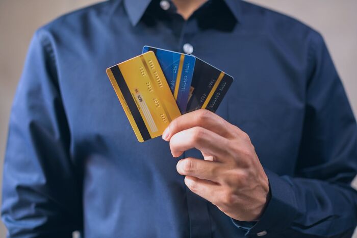 Person holding multiple credit cards in hand, illustrating a glitch in the system exploited for advantage.