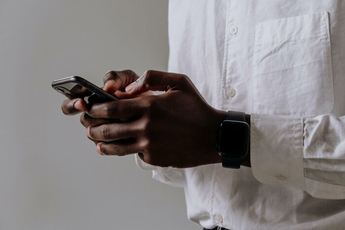 Person wearing a white shirt and smartwatch using a smartphone, illustrating people who became rich out of nowhere.