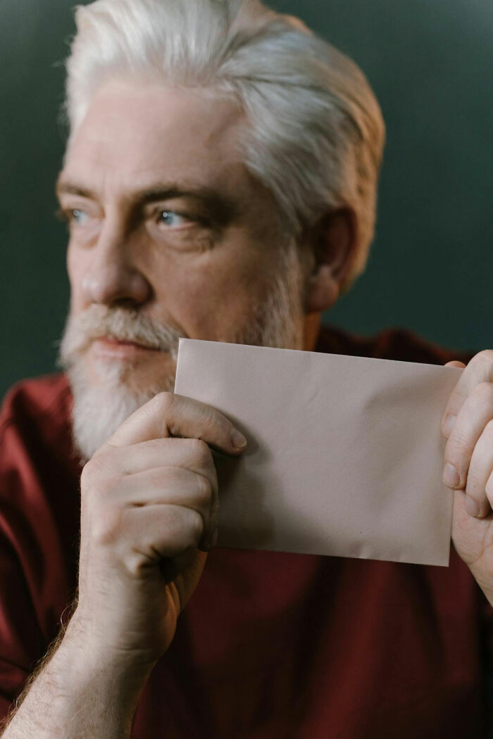 Older man with white hair and beard holding a blank envelope, evoking brilliantly sneaky acts of revenge concept.