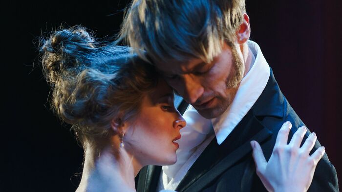 Two actors in period attire performing an intense scene, relating to who played the role of Oppenheimer. Two actors in period attire performing an intense scene, relating to who played the role of Oppenheimer.