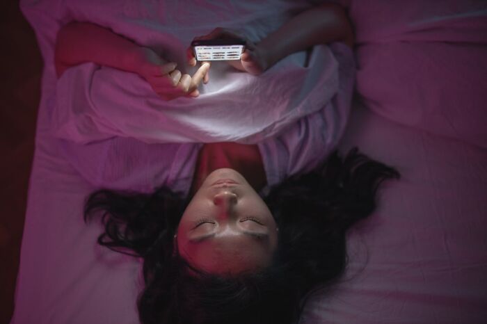 Person lying on bed using smartphone at night, illuminated by screen light, representing life facts that might surprise you.