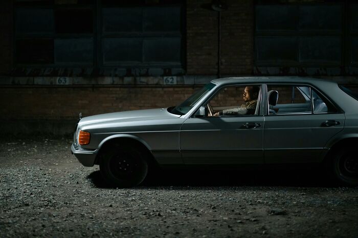 Man sitting alone in a car at night, reflecting on unresolved mysteries people carry with them in a dimly lit area.