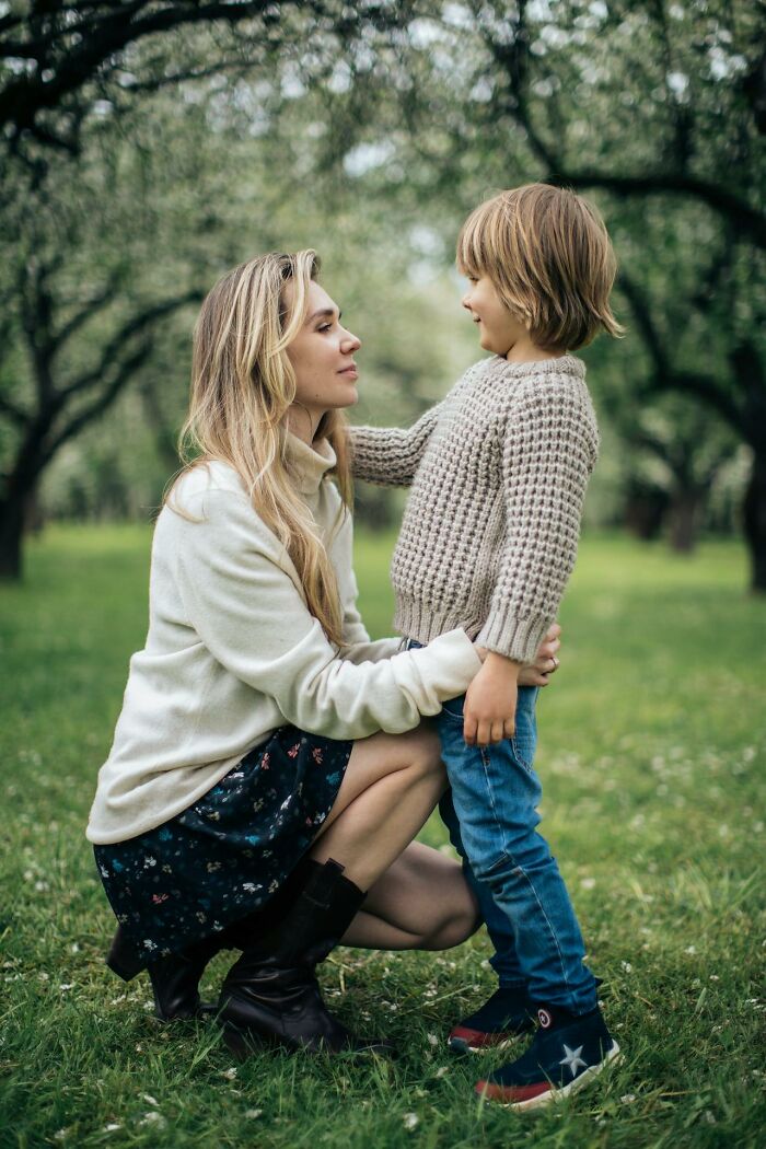 Mother kneeling and talking to her son outdoors, illustrating modern parenting trends in a natural setting.