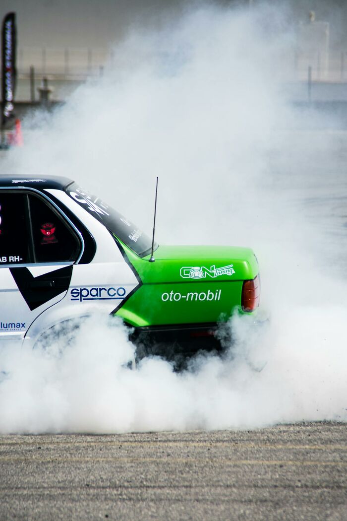 Car drifting on a racetrack with smoke billowing from tires, capturing moments of pure entitlement and chaos.