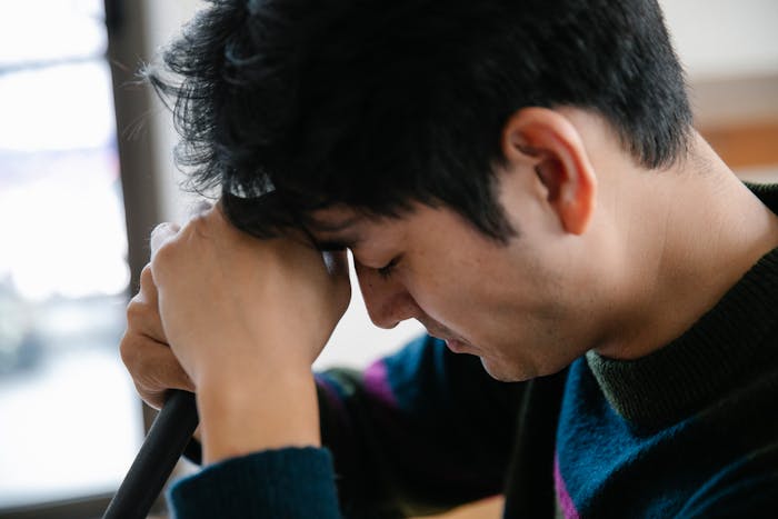 Young man upset and frustrated, resting his forehead on his hands after woman threw away cooked lunches. Young man upset and frustrated, resting his forehead on his hands after woman threw away cooked lunches.