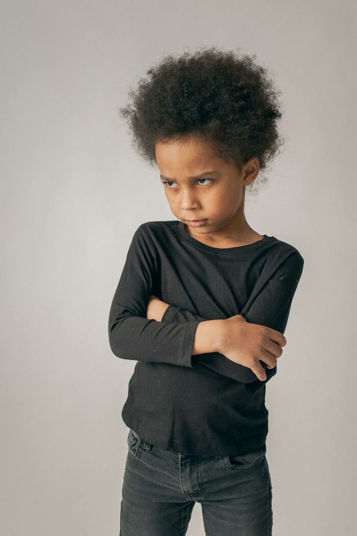 Child looking upset with arms crossed, representing common frustrations in modern parenting trends.