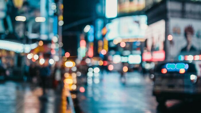 Blurry city street scene at night with colorful lights and silhouettes, illustrating guessing movies from blurry scenes.