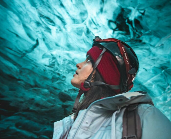 Person wearing a helmet and jacket exploring an ice cave, illustrating disturbing science facts about nature and environments.