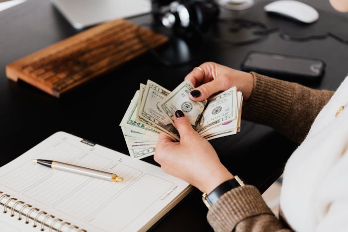 Woman counting cash at desk with planner and pen, illustrating grandparents combine birthday and Christmas gift scenario. Woman counting cash at desk with planner and pen, illustrating grandparents combine birthday and Christmas gift scenario.