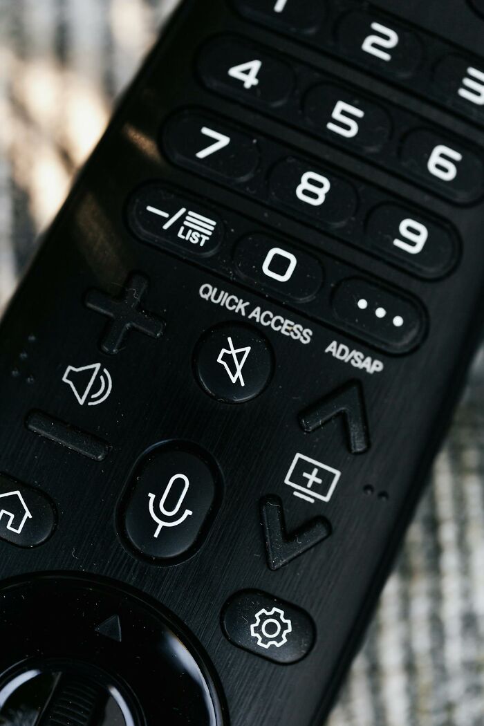 Close-up of a black remote control showcasing buttons with clever icons and functions in the heat of the moment.