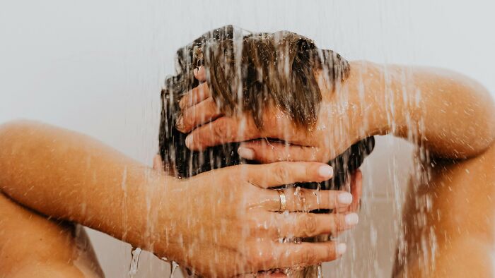 A man washing his hair in a shower, in a close up shot.