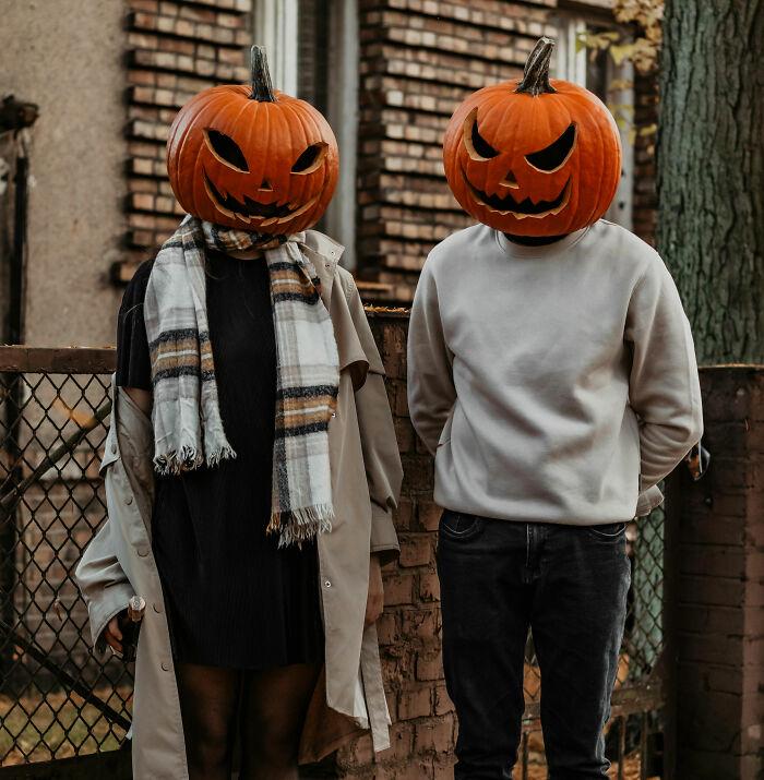 Two people wearing carved pumpkin heads stand outdoors, symbolizing people who became rich out of nowhere.