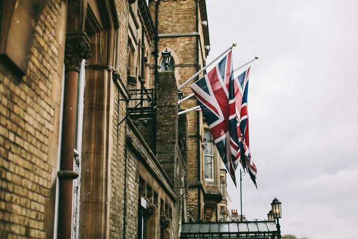 Union Jack flags flying outside a historic brick building in the UK, symbolizing the UK citizenship test challenge. Union Jack flags flying outside a historic brick building in the UK, symbolizing the UK citizenship test challenge.