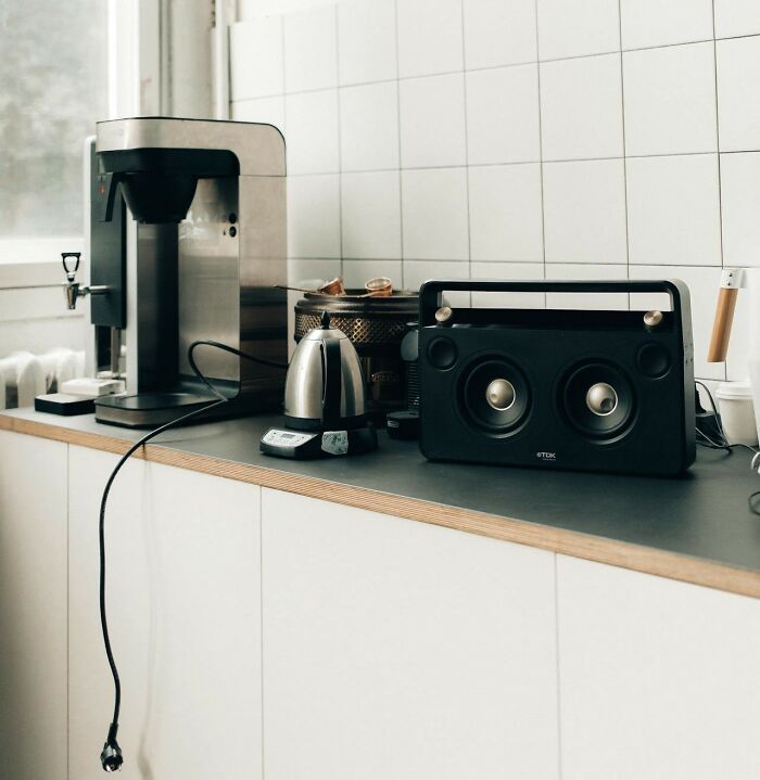 Coffee maker, kettle, and retro speaker on kitchen counter showing small design mistakes with cluttered cable and placement.