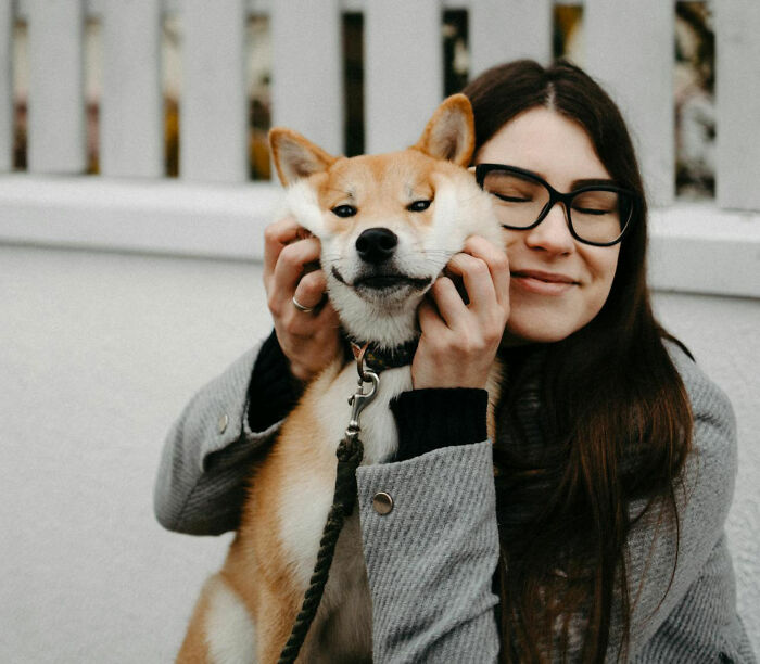 Woman with glasses holding a dog’s face gently, illustrating unusual personal belongings in lost and found collections.