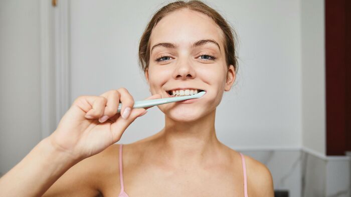A women brushing her teeth in a casual wear. A women brushing her teeth in a casual wear.