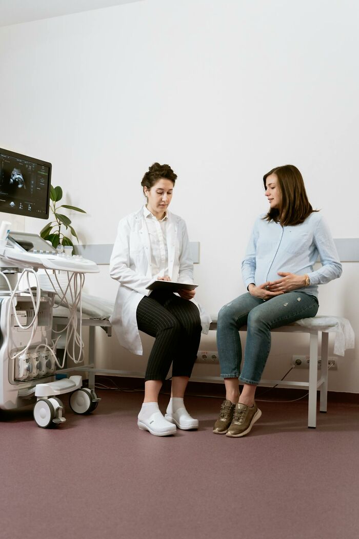 Pregnant woman consulting with a doctor in a medical room near ultrasound machine discussing disturbing facts.