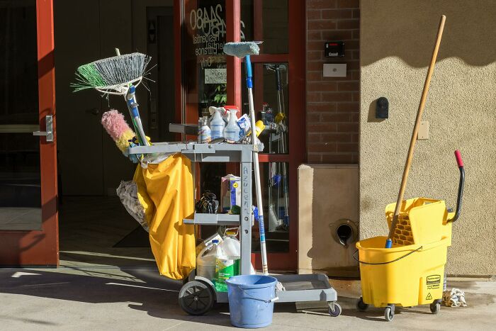 Cleaning cart and supplies outside a building, illustrating small design mistakes in janitorial equipment arrangement.
