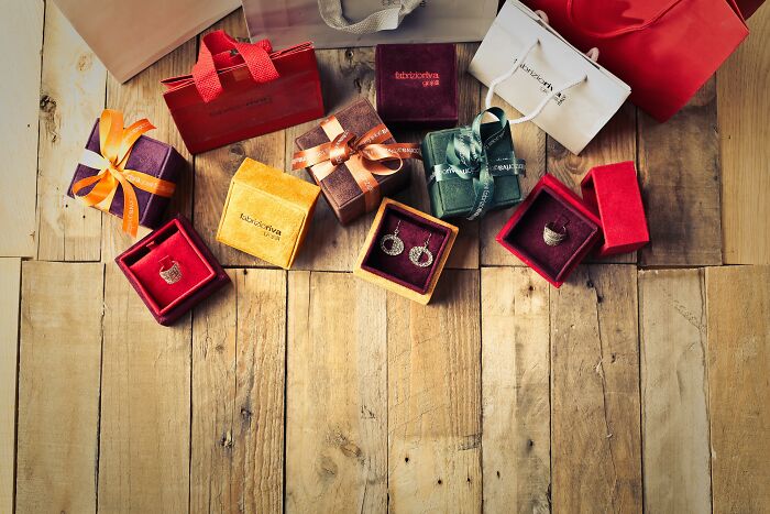 Assorted gift boxes and bags with jewelry displayed on a wooden floor, highlighting horrible gifts people avoid.