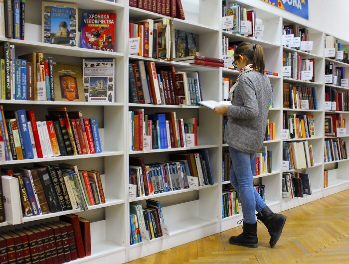 Person reading a book in a library surrounded by shelves, illustrating clever and funny things people say in the moment.